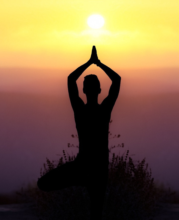 person meditating on mountain to sunset